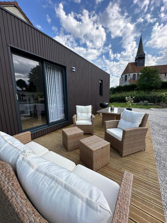 une terrasse en bois avec un canapé et des chaises. dans l'établissement Cottage bungalow le St Vel', à Velennes