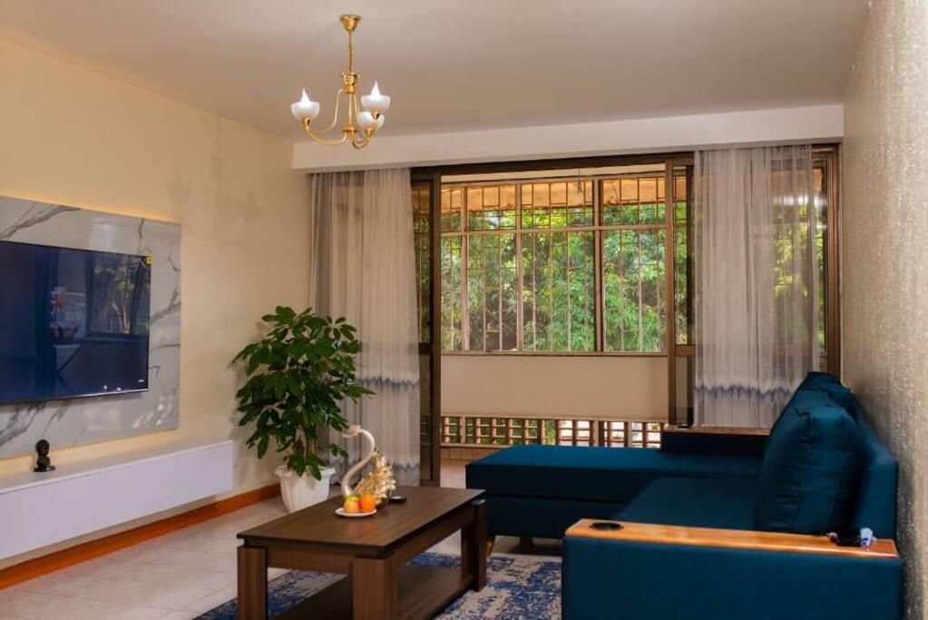 a living room with a blue couch and a large window at Blissful Homes in Kampala