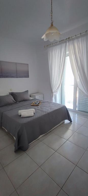 a bedroom with a large bed and a large window at White Beach Appartment in Yerakiní