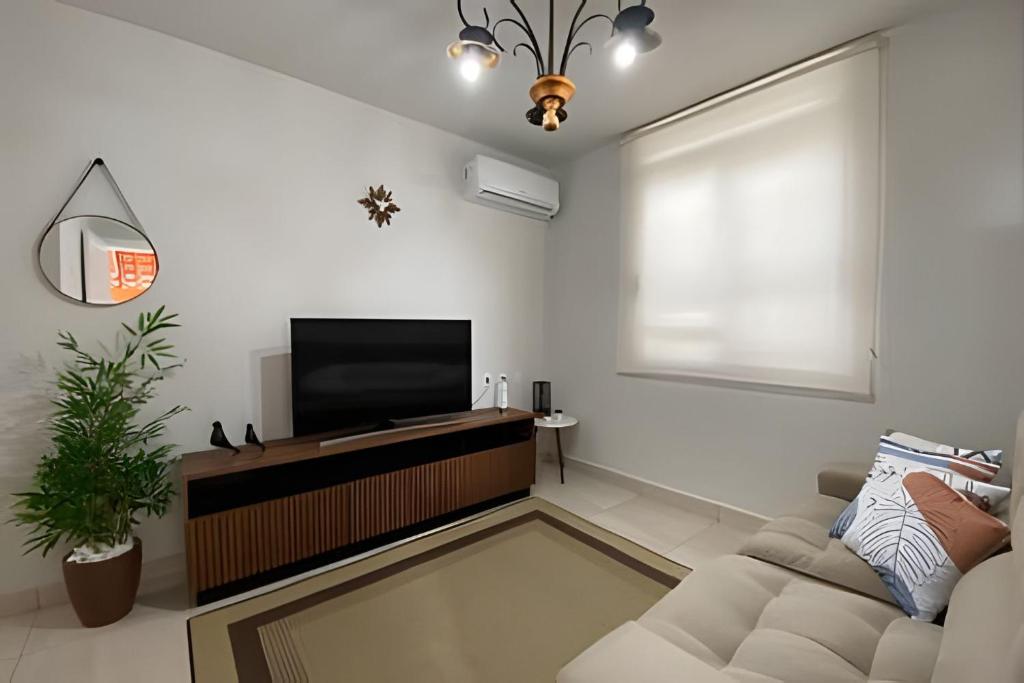 a living room with a television and a couch at Casa Encantos de Araxá in Araxá