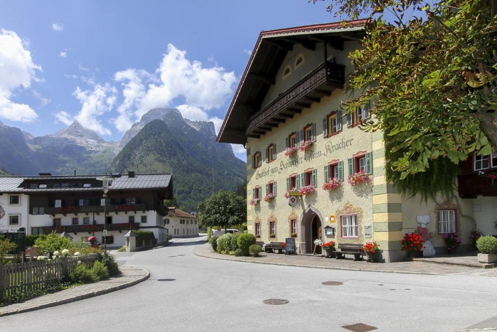 a building on a street with mountains in the background at Hotel - Wirts'haus "Zum Schweizer" in Lofer