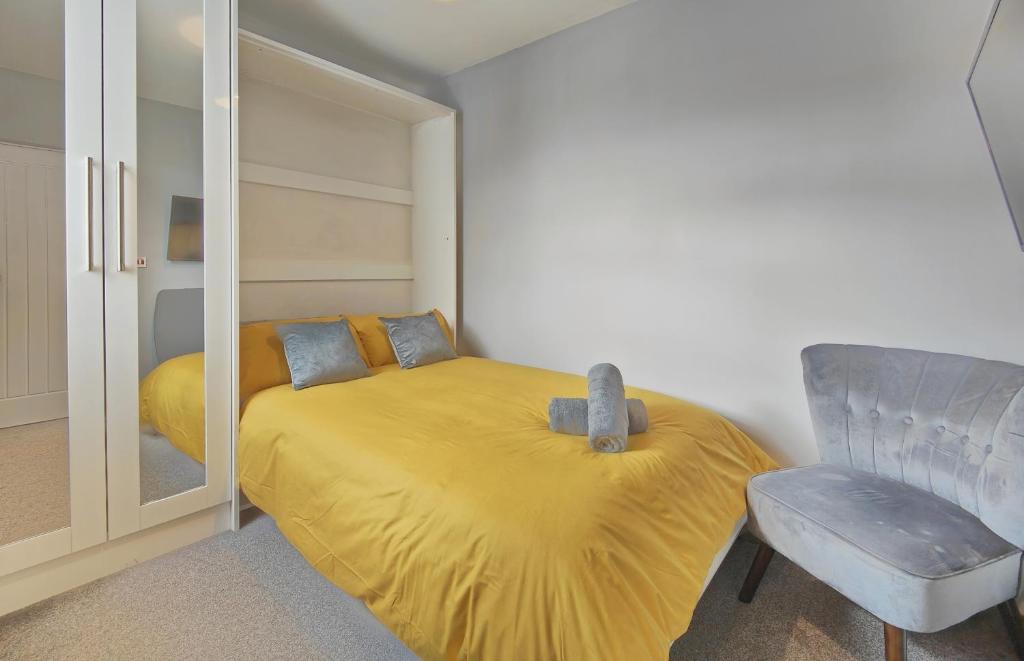 a bedroom with a yellow bed and a chair at Cosy Holiday Studio in Hazel Grove - Self Catering Apartment 1 in Hazel Grove