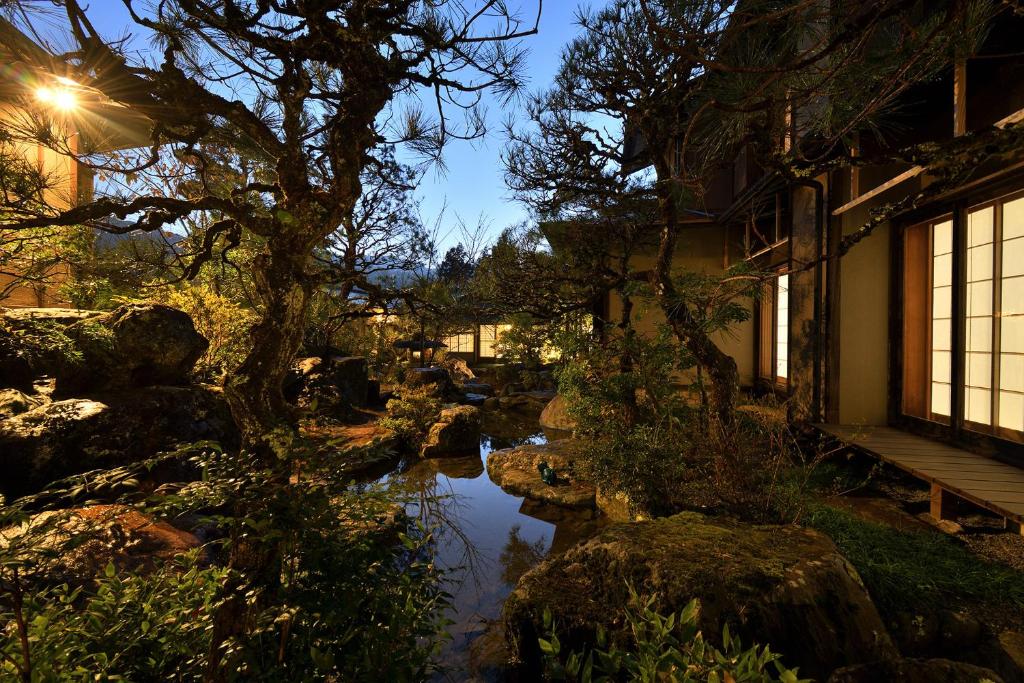 a garden with a pond and a tree and a building at Oni no Sumika in Izu
