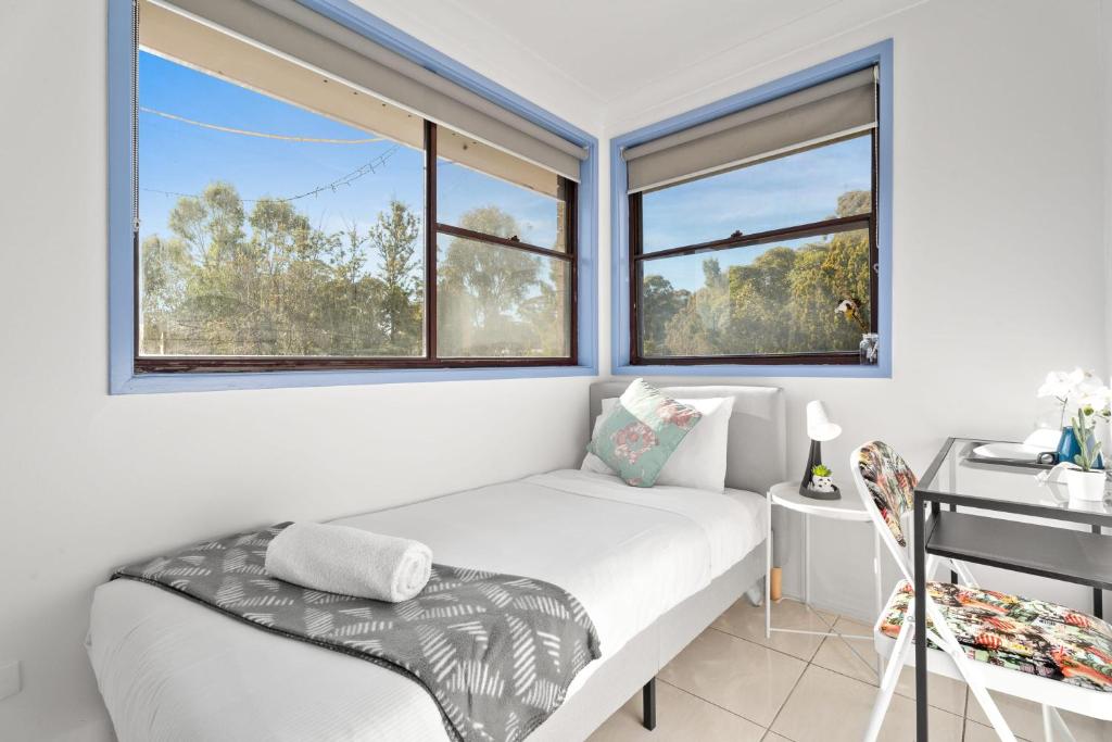 a small bedroom with a bed and two windows at Modern Single Room - Nearby Stations & Eateries - Shared Bathroom in Blacktown