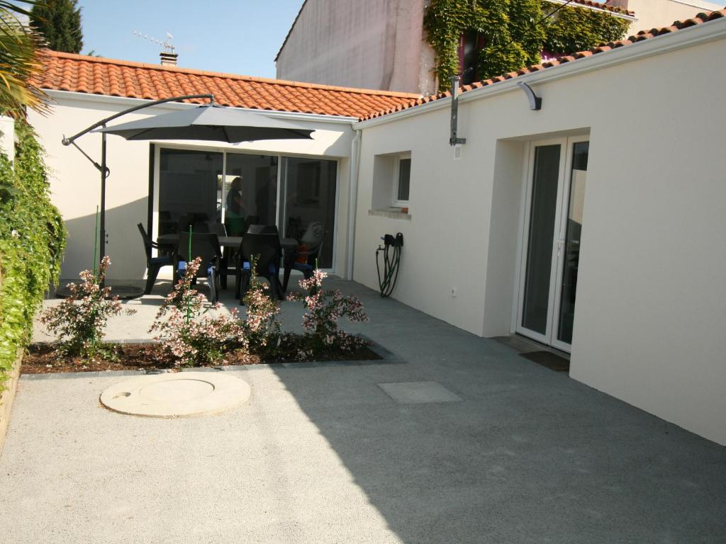 a patio with an umbrella next to a house at Maison rénovée 2 ch, terrasse, proche plage et centre, parking, équipements complets, animaux ok - FR-1-22-356 in La Tranche-sur-Mer