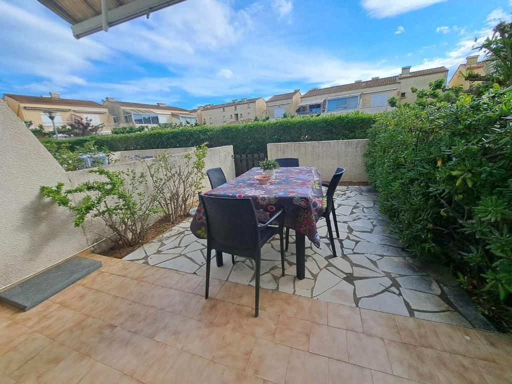 une table et des chaises assises sur une terrasse dans l'établissement Appartement T2 avec Piscine, Terrasse et Parking Privé à Marseillan - FR-1-326-827, à Marseillan