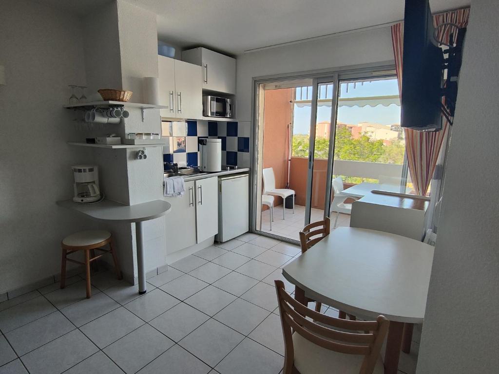 une cuisine et une salle à manger avec une table et une table et des chaises dans l'établissement Appartement Climatisé - Parking - Piscine - Près de la Plage - FR-1-801-6, au Cap d'Agde