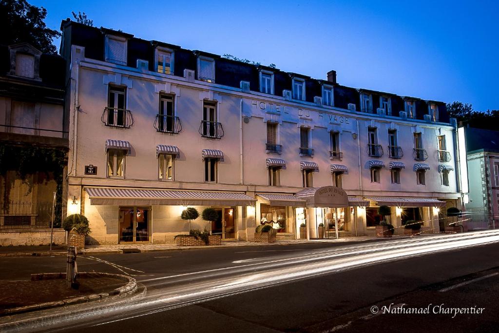 a large white building on a city street at night at Logis Hôtel Le Rivage in Gien