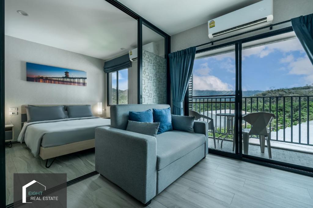 - une chambre avec un lit, un canapé et un balcon dans l'établissement Cozy Studio Apartment at Naiyang Beach G507, à Phuket