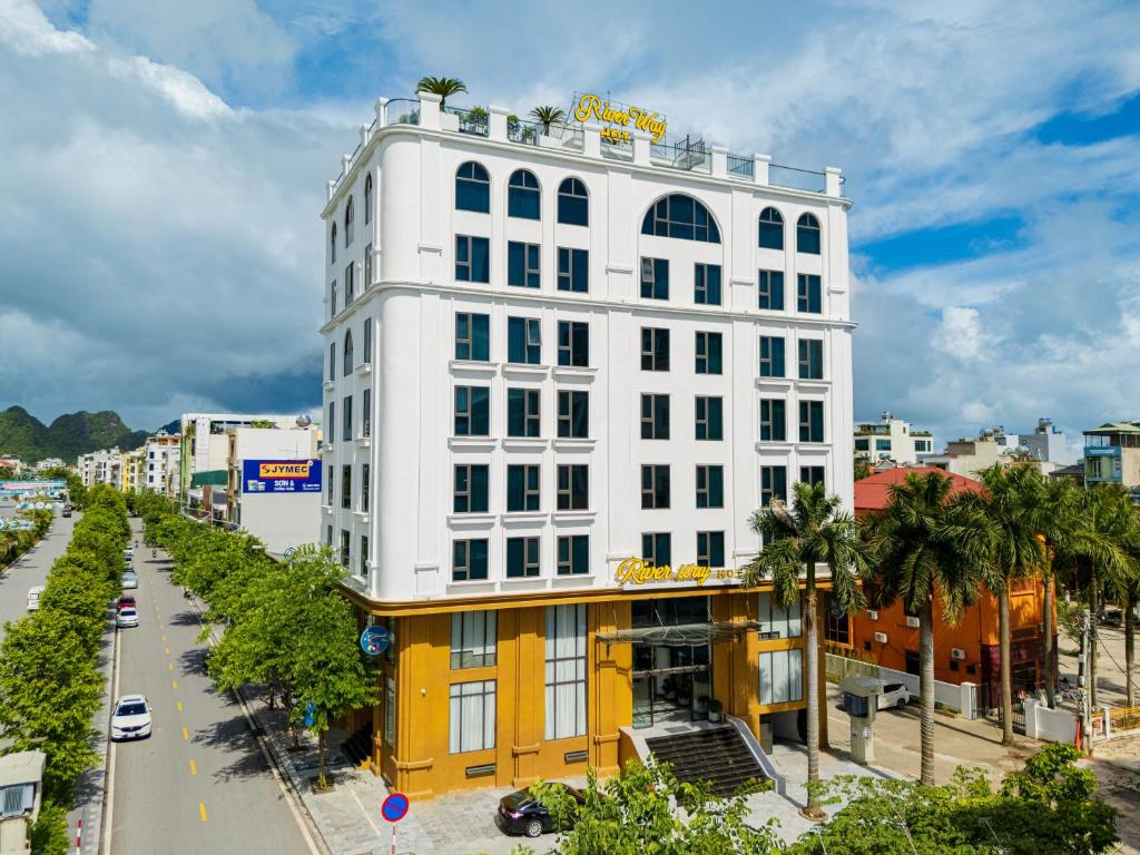un edificio blanco y amarillo en una calle de la ciudad en River Way Hotel Ha Long, en Ha Long