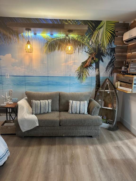 a living room with a couch and a palm tree mural at Studio Apartment 5 minutes from beach in St Petersburg