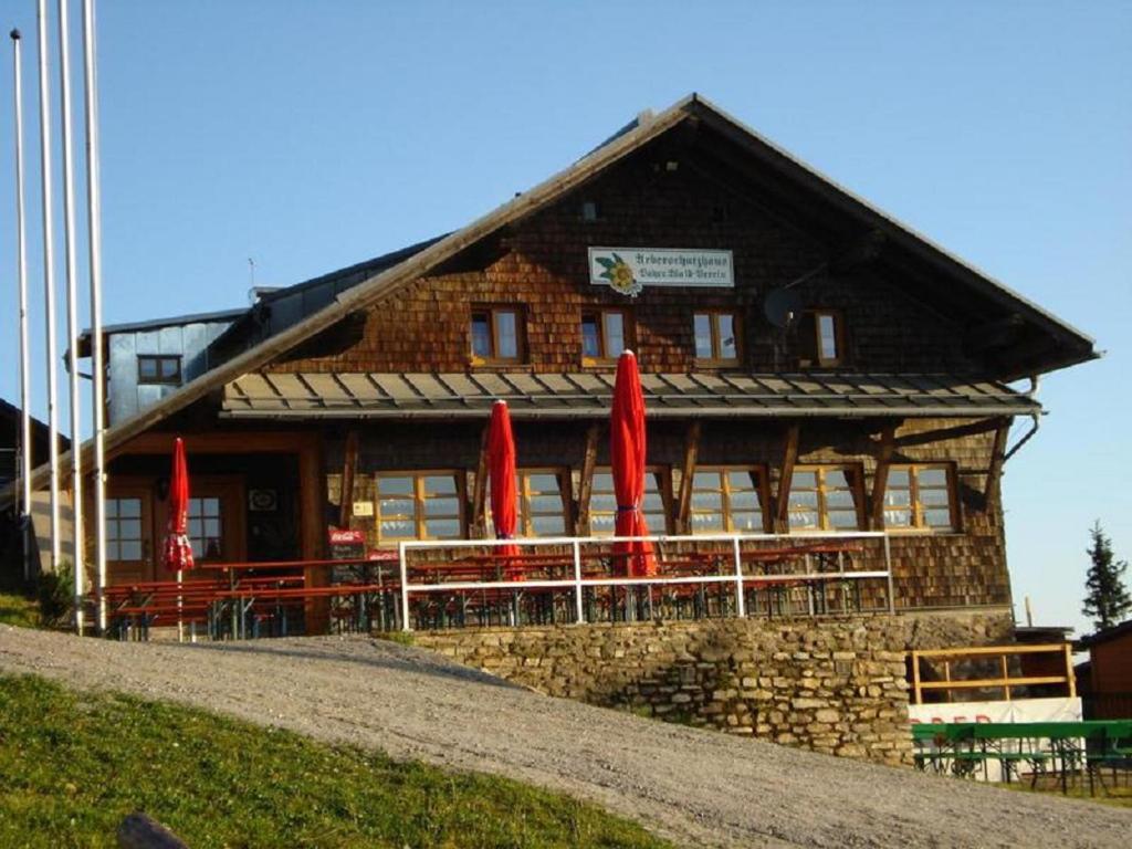 ein Gebäude mit roten Sonnenschirmen davor in der Unterkunft Arberschutzhaus in Bayerisch Eisenstein