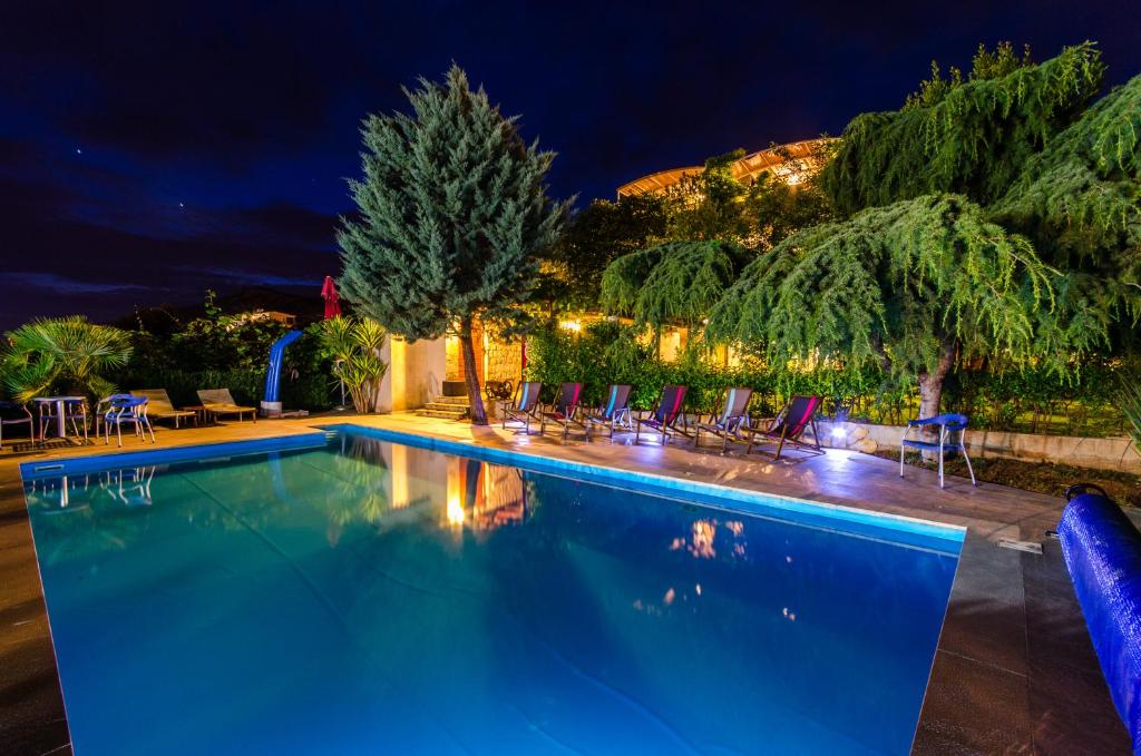 a swimming pool at night with chairs and trees at Villa Marcelina in Seget Vranjica