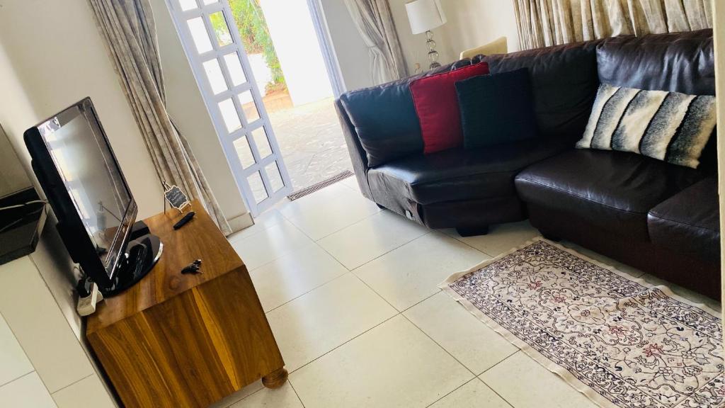 a living room with a black leather couch and a television at La Lucia Sleepover in Durban