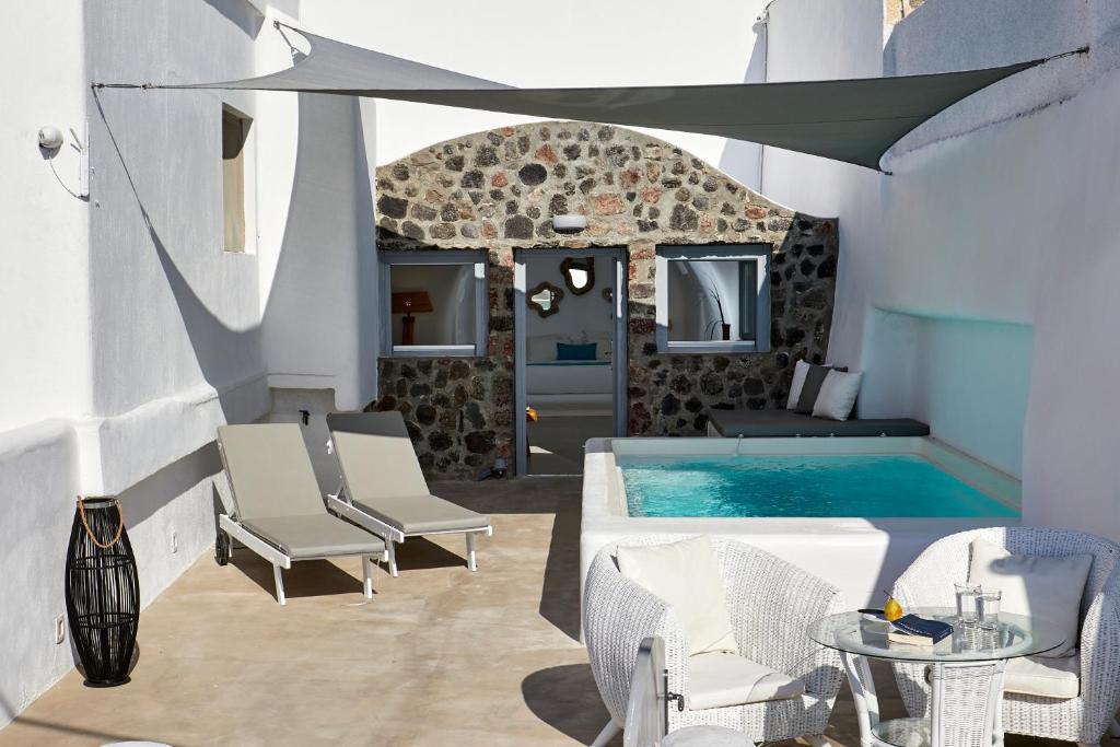 una piscina con 2 sillas, una mesa y una piscina en Imerovigli Iliovasilema Villa, en Imerovigli