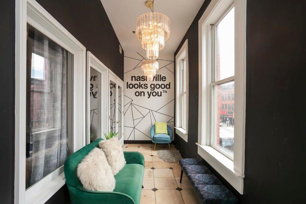a living room with a green couch and a chandelier at Grand Loft ON THEE Broadway Strip in Nashville