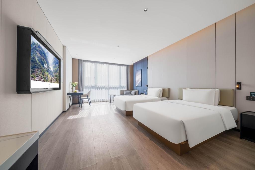 a hotel room with two beds and a flat screen tv at Atour Hotel Chongqing Wanzhou Wanda Beibin Avenue in Wanzhou