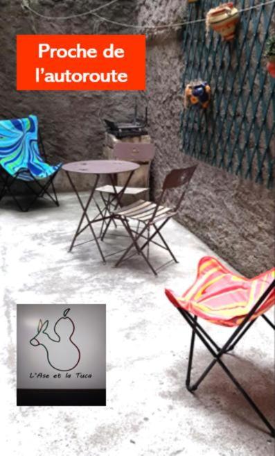 un groupe de chaises, une table et un panneau dans l'établissement L'ase et la tuca, à Bessan