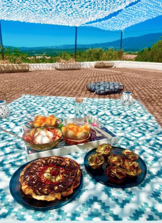 a table with plates of food on a blue table cloth at Là où le Ciel est né Beau mas pierres et contemporain sur grande propriété vue Mont Ventoux dentelles de Montmirail in Blauvac