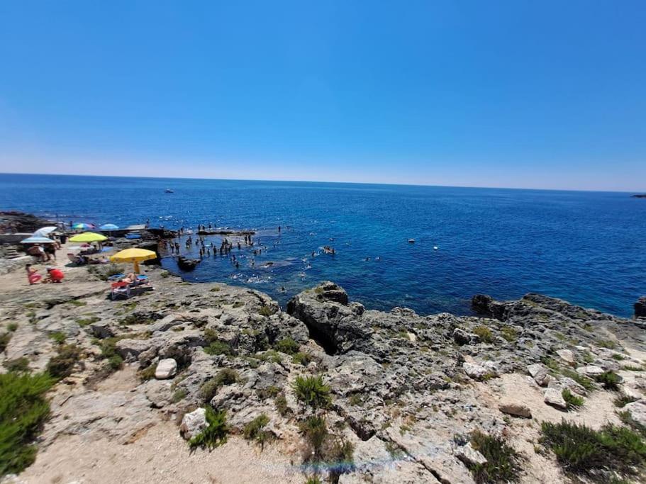 a group of people on a beach with umbrellas at Casa Vacanza fronte mare Il Rifugio di Alice in Andrano