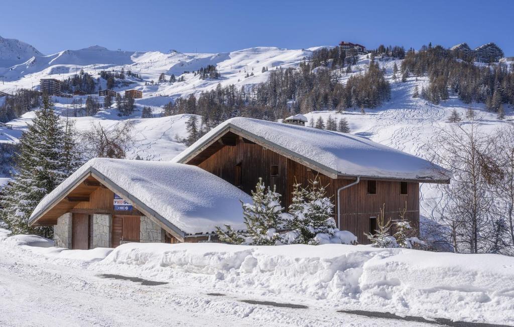un bâtiment recouvert de neige sur une montagne dans l'établissement Odalys Chalet L'Arpette Lodge, à La Plagne Tarentaise