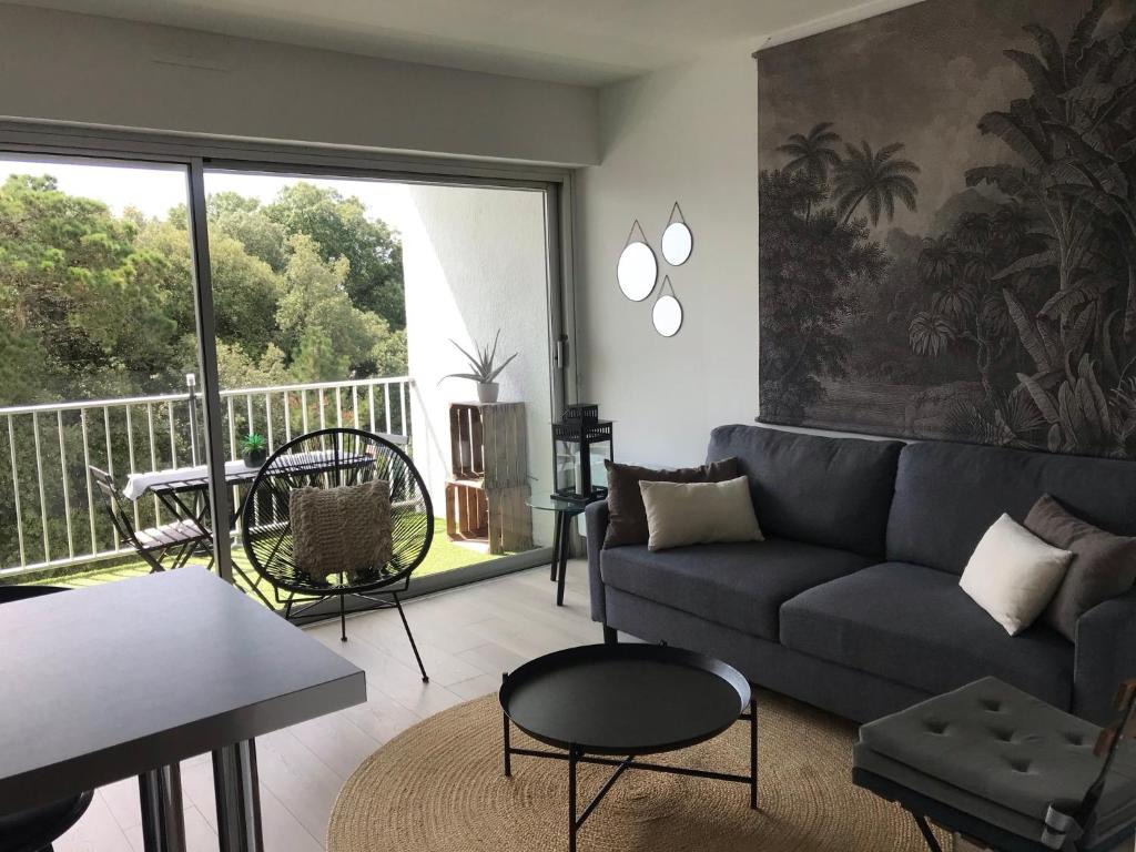 d'un salon avec un canapé et un balcon. dans l'établissement Au calme du bois du Pouliguen plage et port à pied, au Pouliguen