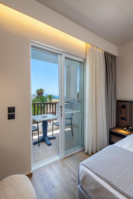 a hotel room with a bed and a balcony with a table at Kalimera Mare in Kardamaina