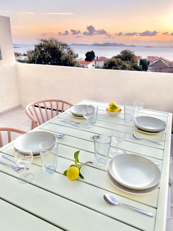 a white table with plates and glasses on it at Lukenda Rooms - Boutique Apartments with view of Adriatic Sea in Pakoštane