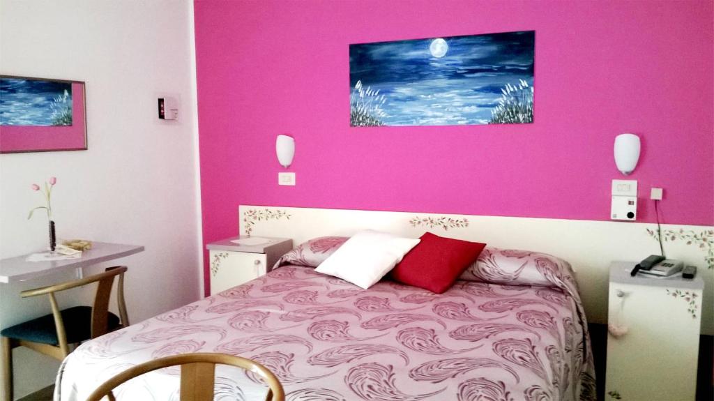 Un dormitorio con una pared rosa y una cama en Hotel Astor, en Silvi Marina