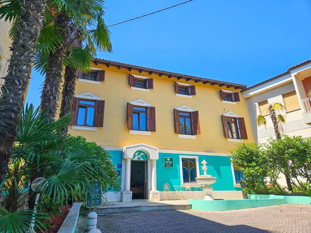 a yellow and blue house with palm trees at Villa Kontesa in Lovran