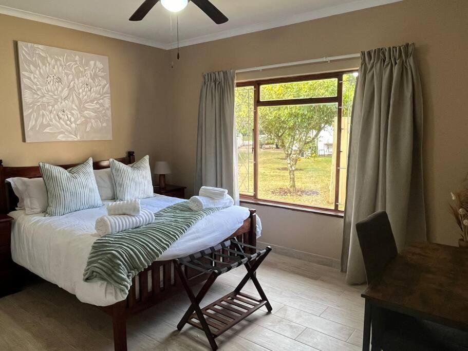 ein Schlafzimmer mit einem Bett und einem großen Fenster in der Unterkunft Forest Drive Cottage in Kloof