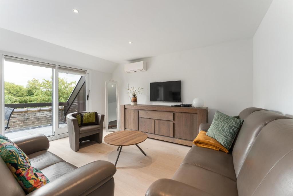 un salon avec un canapé et une télévision dans l'établissement Marlie s Home - comfort stadsapp met zonnig terras, à Nieuport
