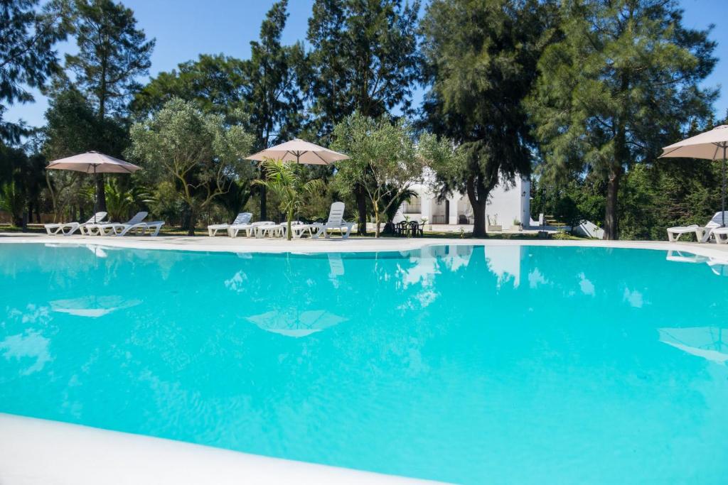 a swimming pool with blue water and umbrellas at Chalet El Molino in Chiclana de la Frontera
