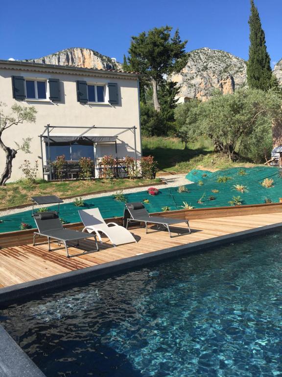 a pool with two lounge chairs and a house at Les Claux des Oliviers in Moustiers-Sainte-Marie