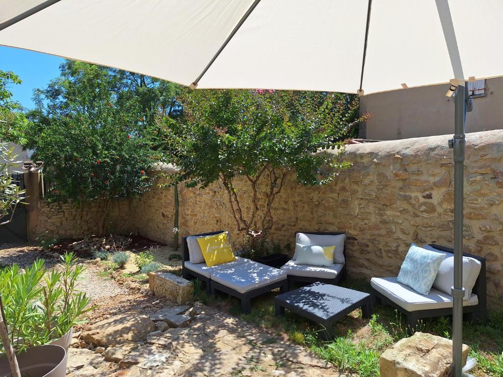 une terrasse avec 3 chaises et un parasol dans l'établissement Maison de charme village entre Vignes et Lavandes, à Le Pin