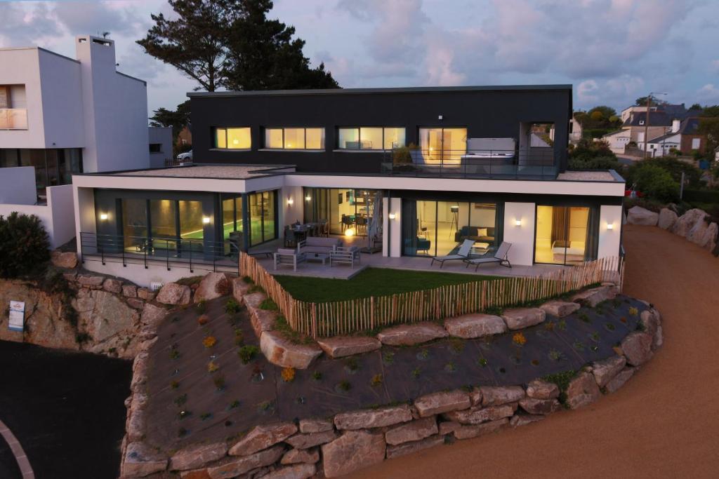 une grande maison noire avec un mur en pierre dans l'établissement Villa des Agapanthes, à Pleumeur-Bodou