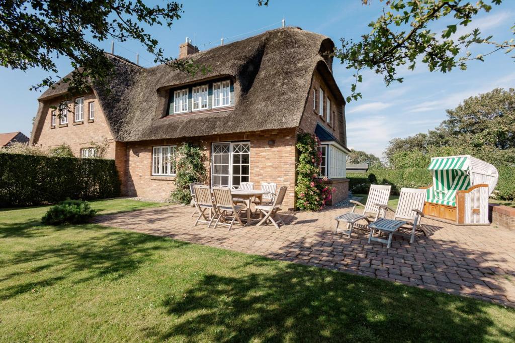 un cottage con il tetto di paglia, un tavolo e delle sedie di LandLust a Borgsum