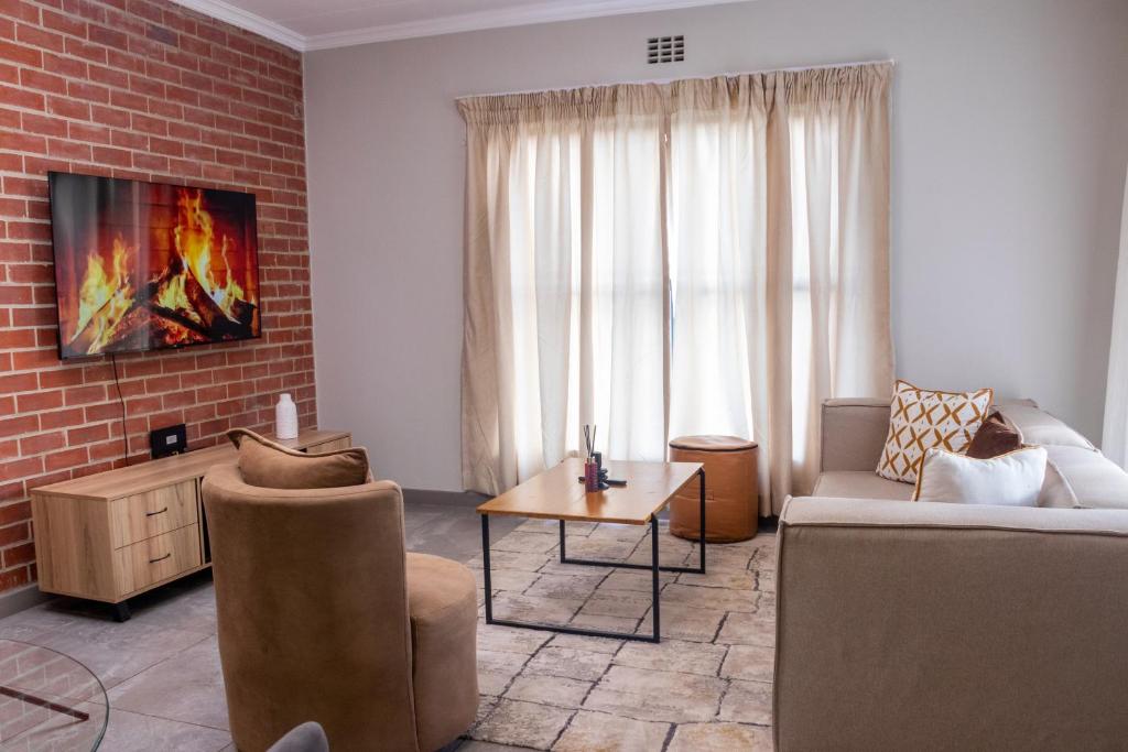 un soggiorno con un divano e un muro di mattoni di 8 Elizabeth place - Beautiful self catering 1 Bedroom Apartment next to Kyalami Racetrack in Midrand with Free Wifi Local swimming pool Gym and Restaurant - perfect for a couple a Midrand