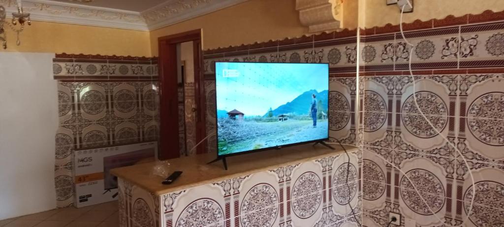a flat screen tv hanging on a wall at Grand Appt près de la mer in Hajreien