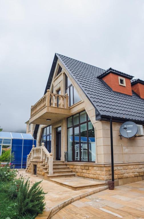 a house with a black roof with a deck at Viva hotel Gabala with outdoor pool ,Sauna and Waterfall in Gabala