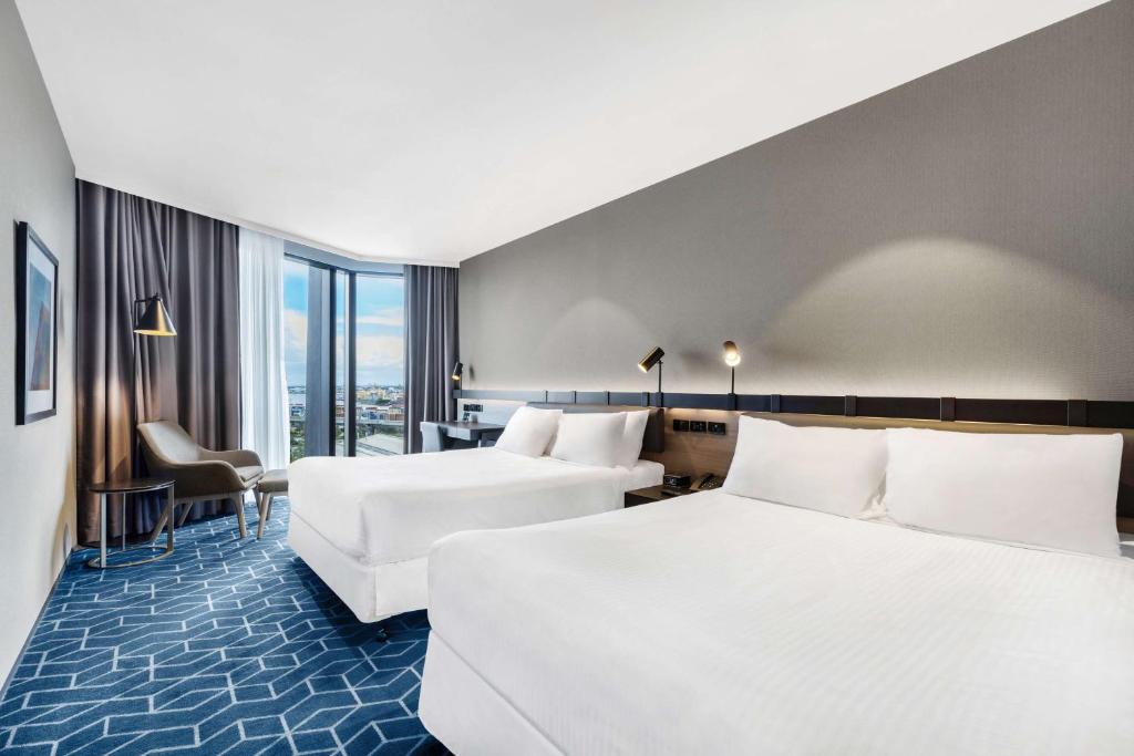 a hotel room with two beds and a desk at Vibe Hotel Melbourne Docklands in Melbourne