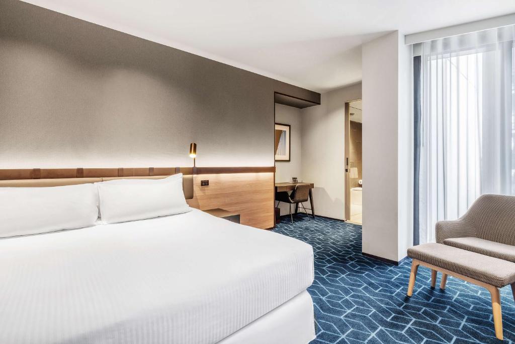 a hotel room with a bed and a chair at Vibe Hotel Melbourne Docklands in Melbourne