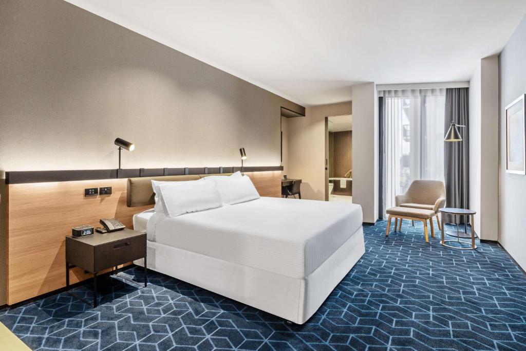 a hotel room with a bed and a chair at Vibe Hotel Melbourne Docklands in Melbourne