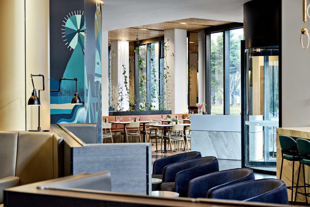 a restaurant with blue chairs and tables and windows at Vibe Hotel Melbourne Docklands in Melbourne