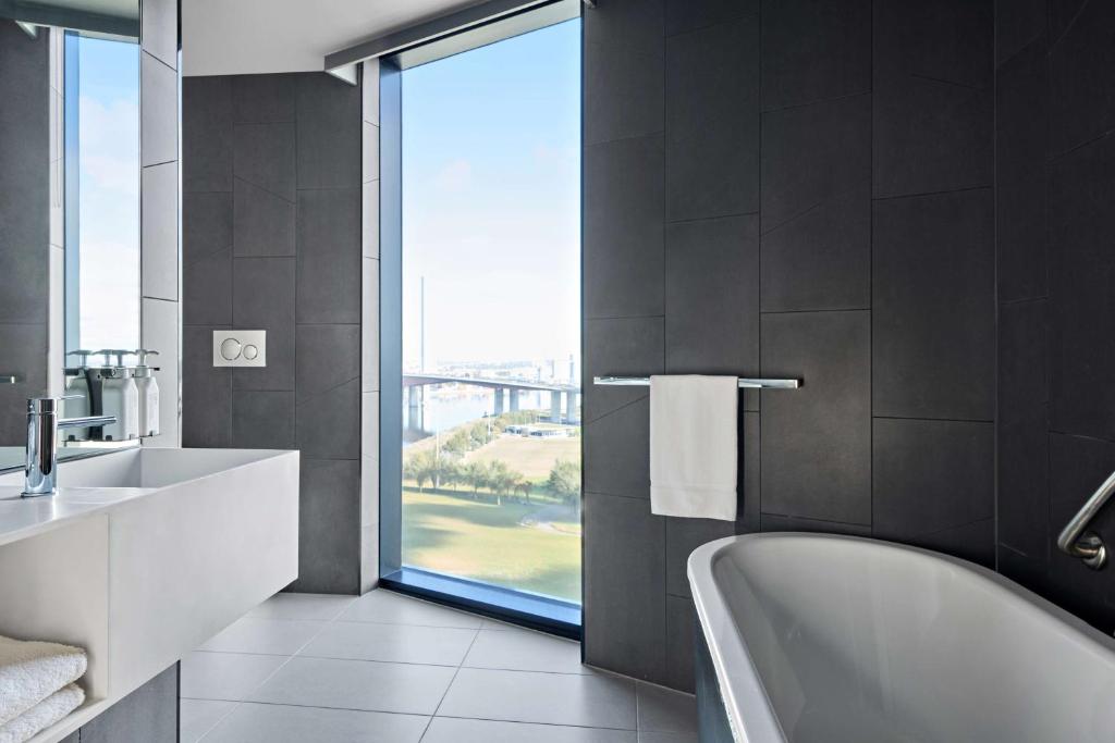 a bathroom with a tub and a sink and a window at Vibe Hotel Melbourne Docklands in Melbourne