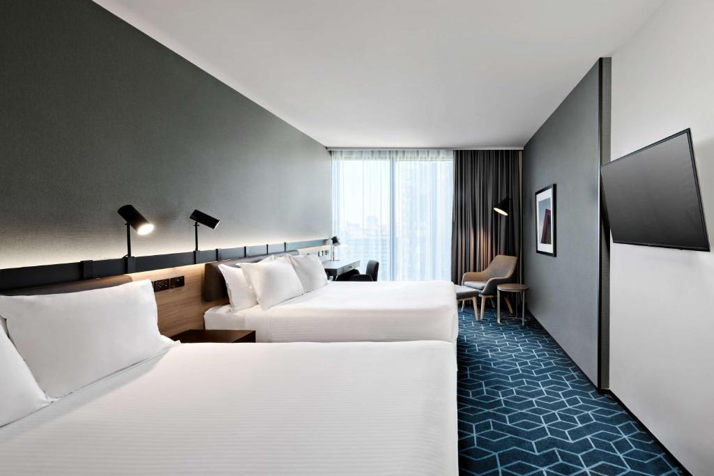 a hotel room with two beds and a desk at Vibe Hotel Melbourne Docklands in Melbourne