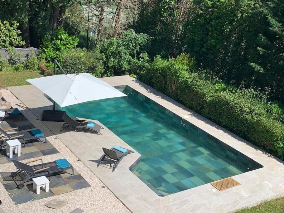 a swimming pool with an umbrella and chairs and a table and an umbrella at Spacious villa for family holidays in Valbonne