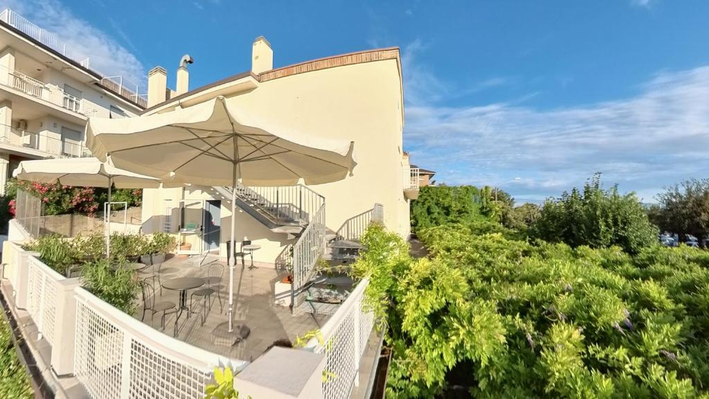 a balcony with an umbrella and tables and chairs at Hotel Tritone in Trieste