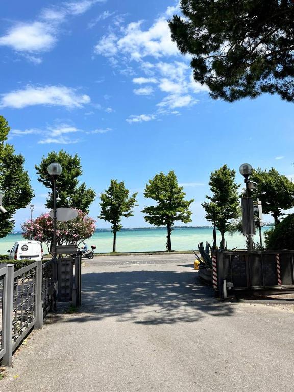 a gate leading to a beach with trees and the ocean at DIVE RIVE LUXURY Apartment in Desenzano del Garda