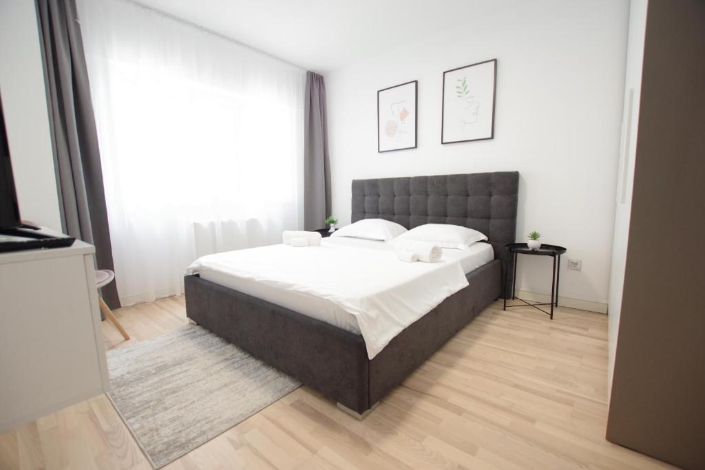 Un dormitorio con una cama grande con sábanas blancas. en Himson-Grey Apartment, en Iaşi